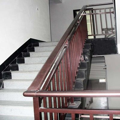 Στον τοίχο τοποθετημένη γυάλινη σκάλα χειροκίνηση με ακροβάθμια από ανοξείδωτο χάλυβα και σύγχρονη εμφάνιση σχεδιασμού
